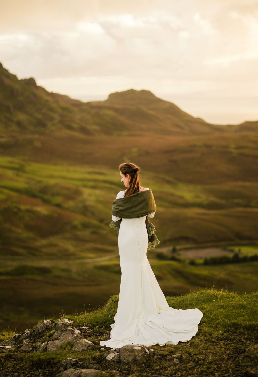 Bride on top of a cliff in Scottish Highlands' elopement at sunrise.