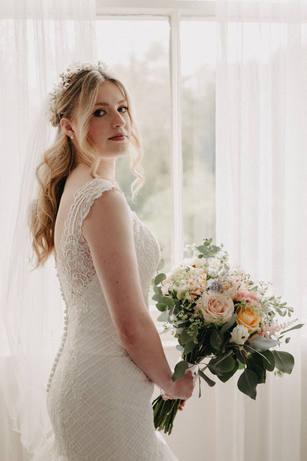 Bride holding flowers during preparations at Scottish castle wedding.