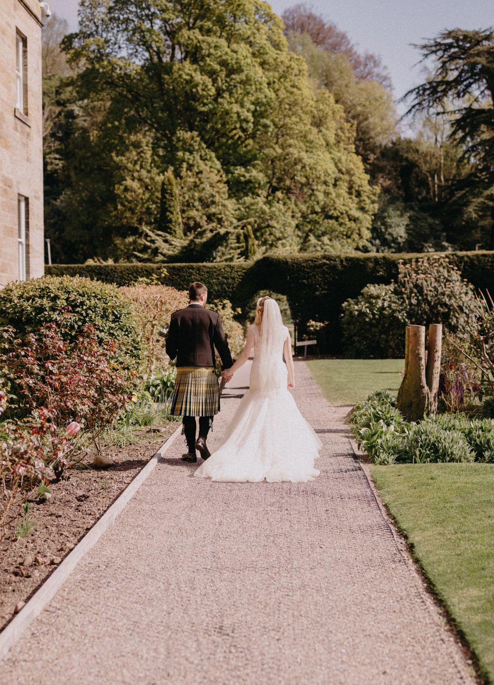 Bride and groom walking in the gardens during Scottish castle wedding.