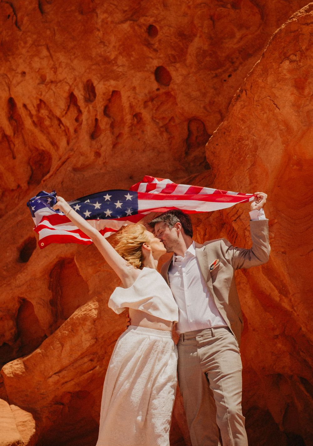 Bride & groom kissing against a backdrop of red rocks in American destination wedding in Nevada, USA.