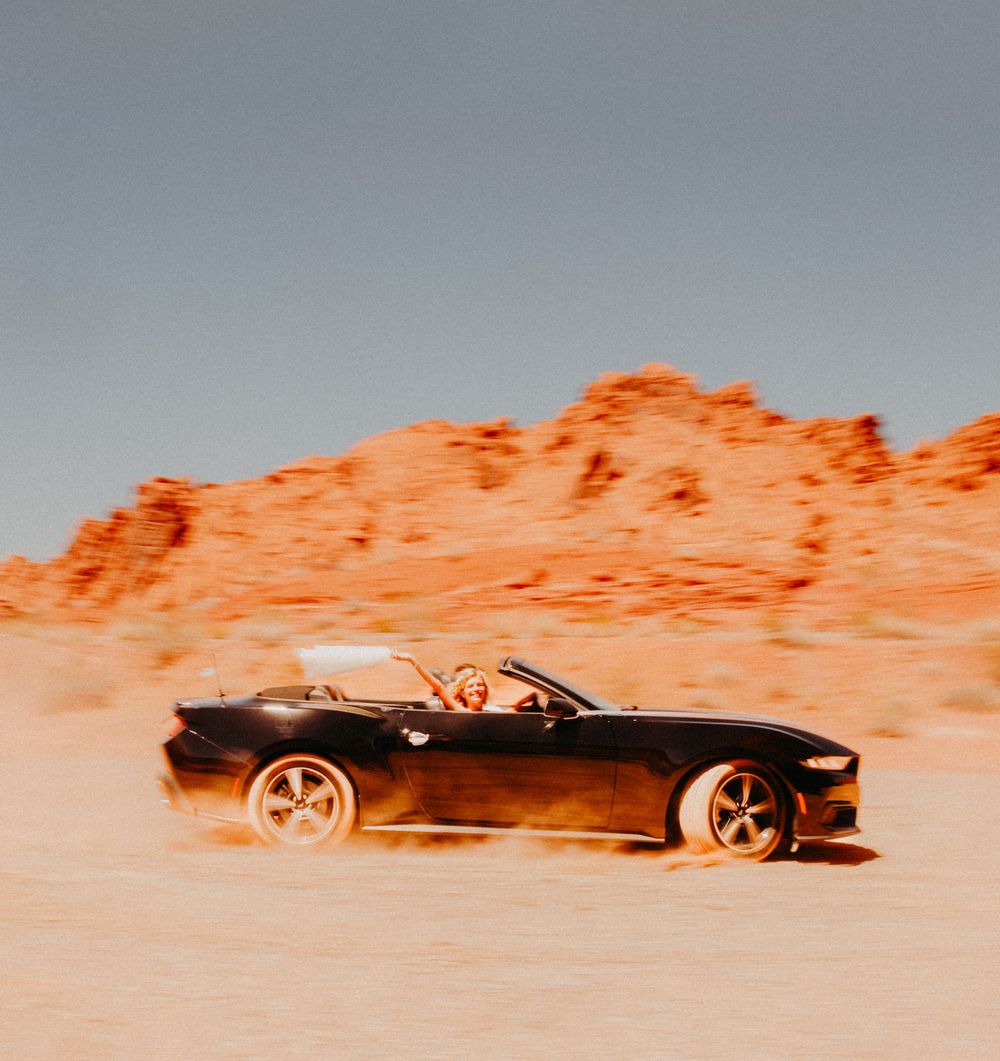 Bride holding her veil in a mustang in the desert during destination wedding in Nevada, USA.