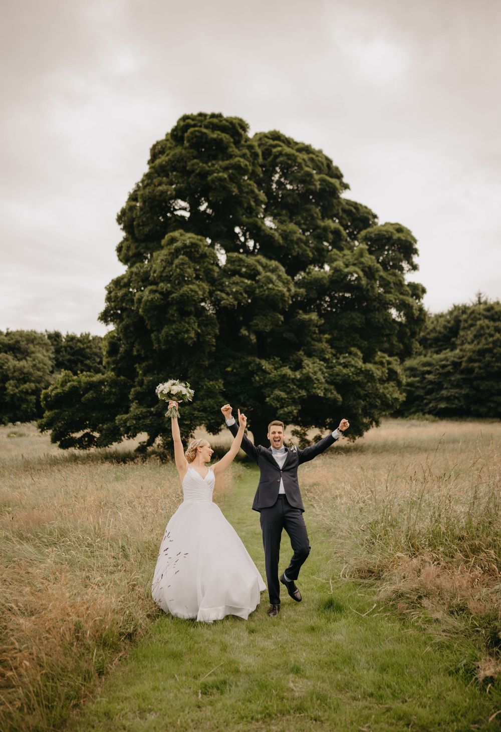 Bride and groom celebrating in the countryside at Scottish castle wedding.