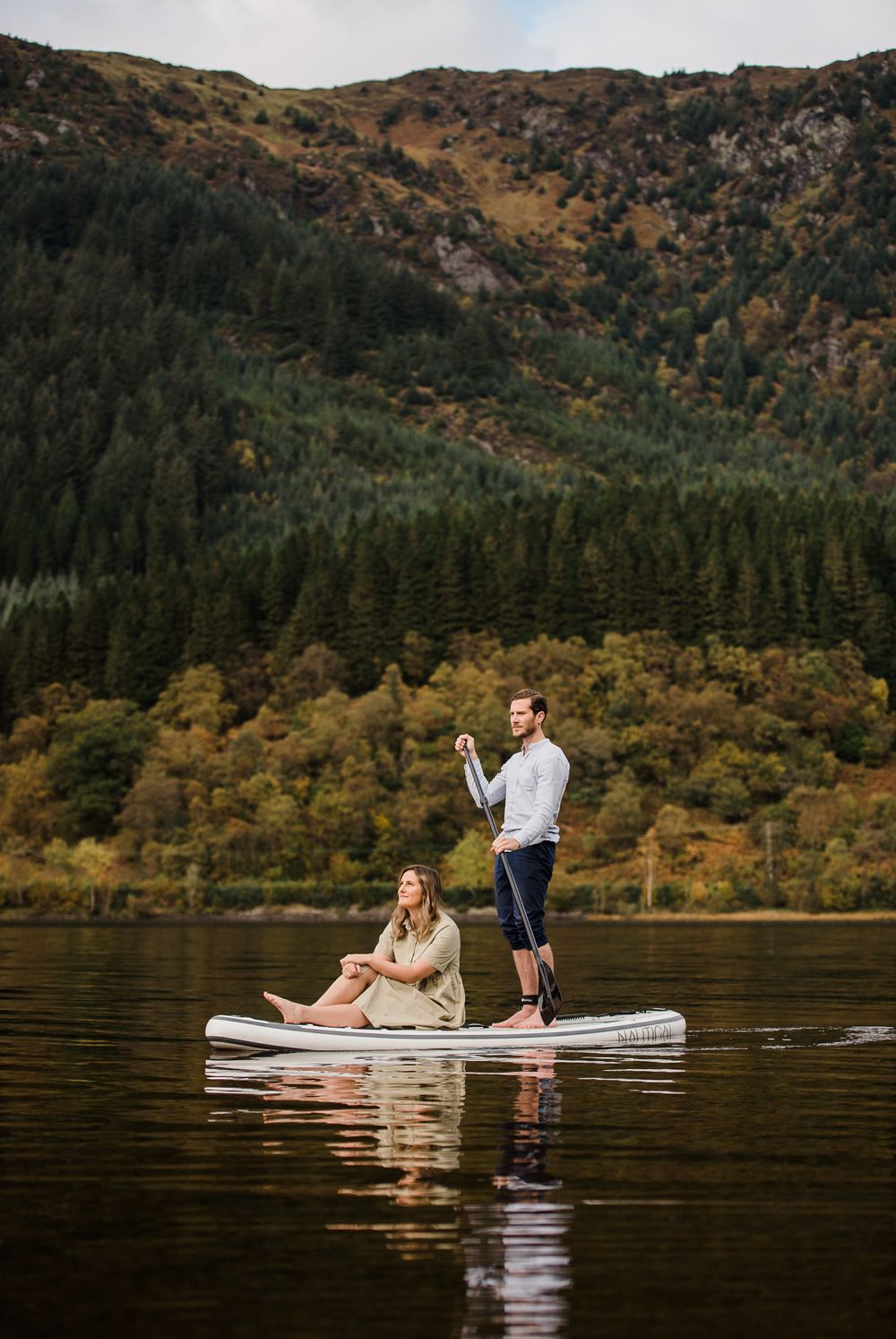 Couple on paddle board SUP on a lake in the Scottish Highlands.