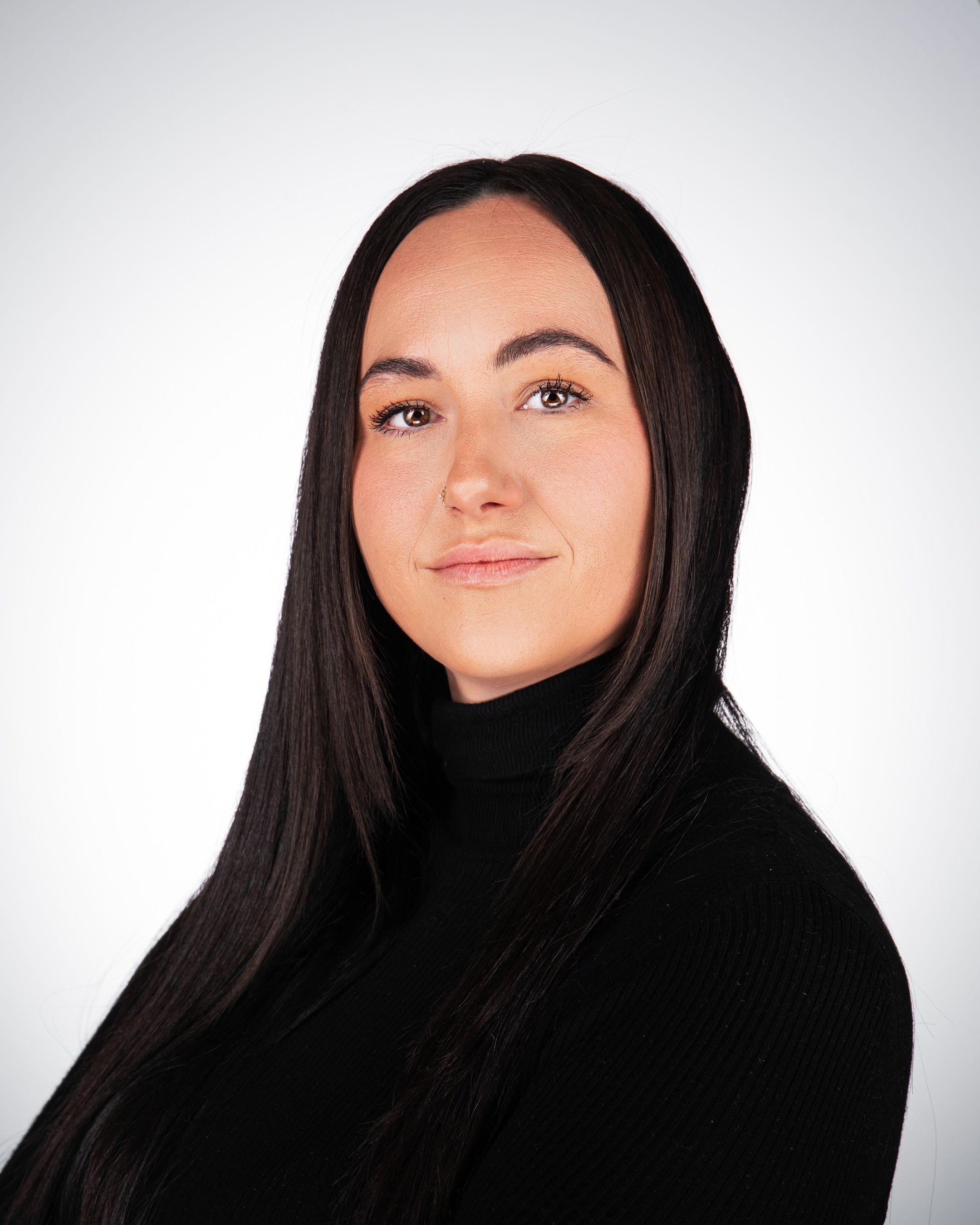 Professional headshot portrait of someone in a black turtleneck sweater against a light gray background.
