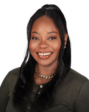 Professional headshot of a person with long black hair wearing a dark olive button-up shirt and a gold chain necklace.