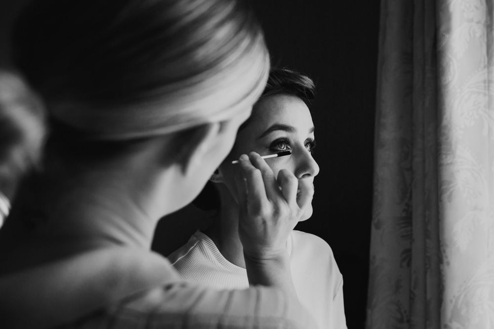Wedding day makeup preparation by window in black and white  London wedding photographer. The landmark