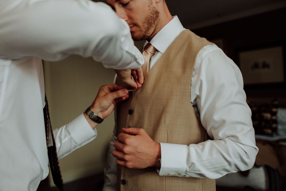 Close-up shot of formal wear preparations showing details of a tan vest and white dress shirt.