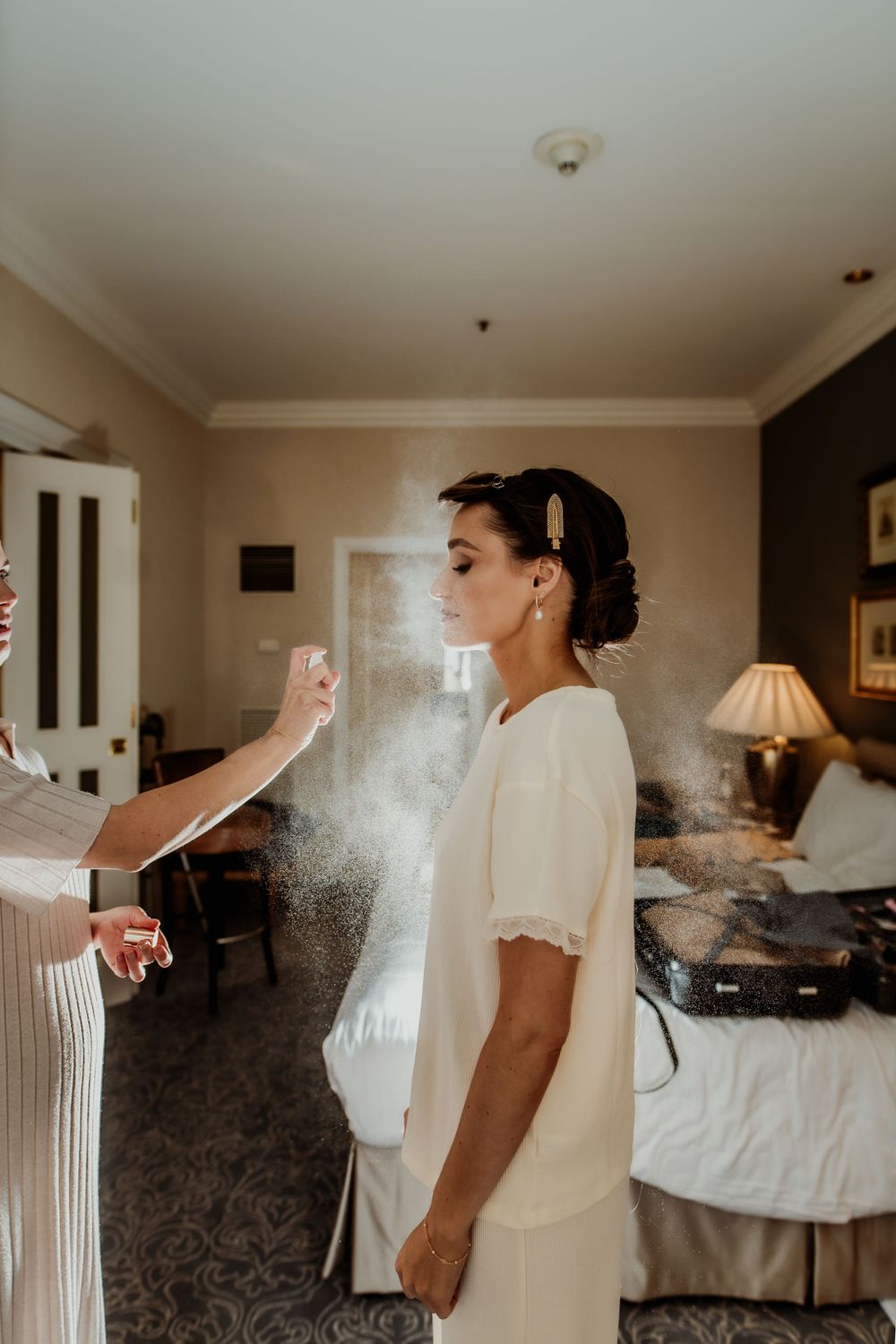 Getting ready scene with hairspray being applied in a hotel room  London wedding photographer. The landmark