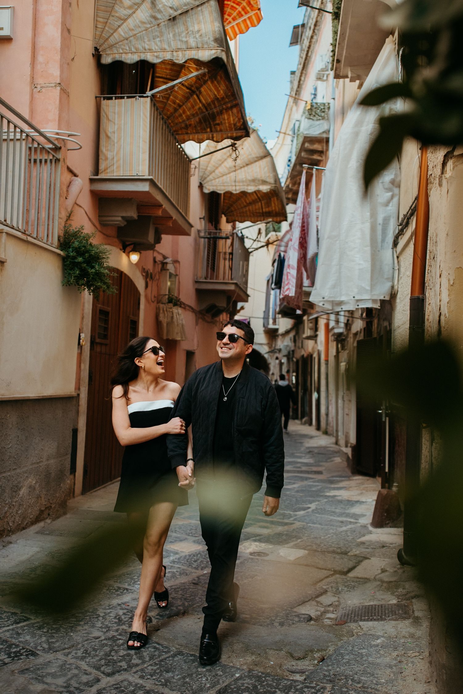 Couple walking through narrow European alleyway with pink walls.