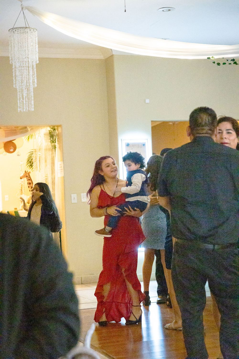 Event guests mingling and dancing in a decorated indoor venue with white drapes and chandeliers.