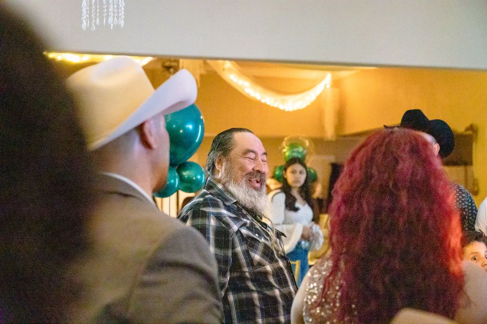 Lively party scene with guests celebrating under decorative lighting and teal balloons.