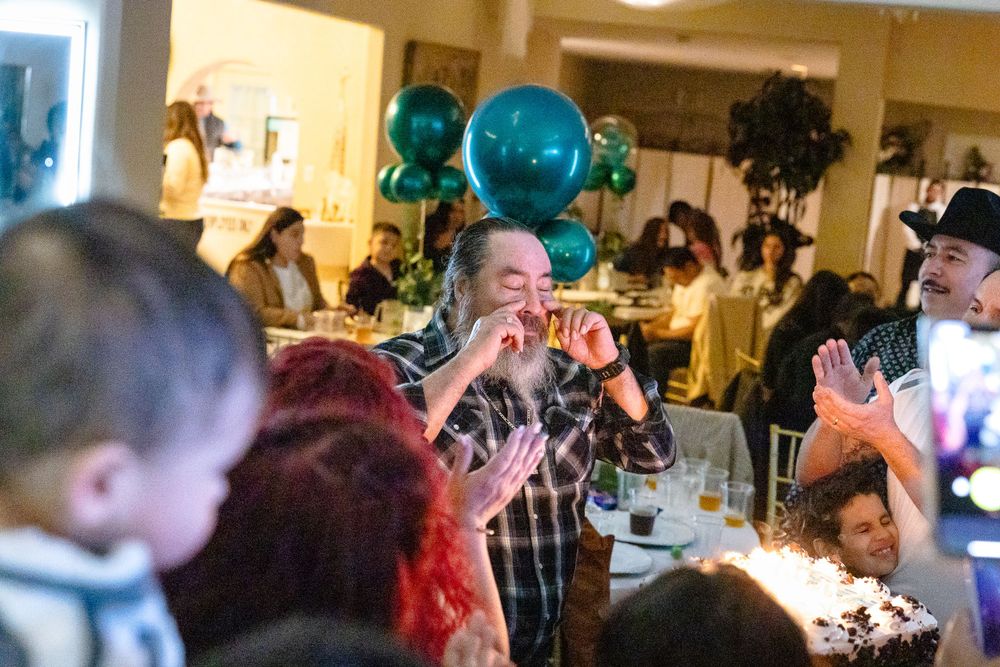 A festive celebration with teal balloons and guests gathered in an indoor venue.