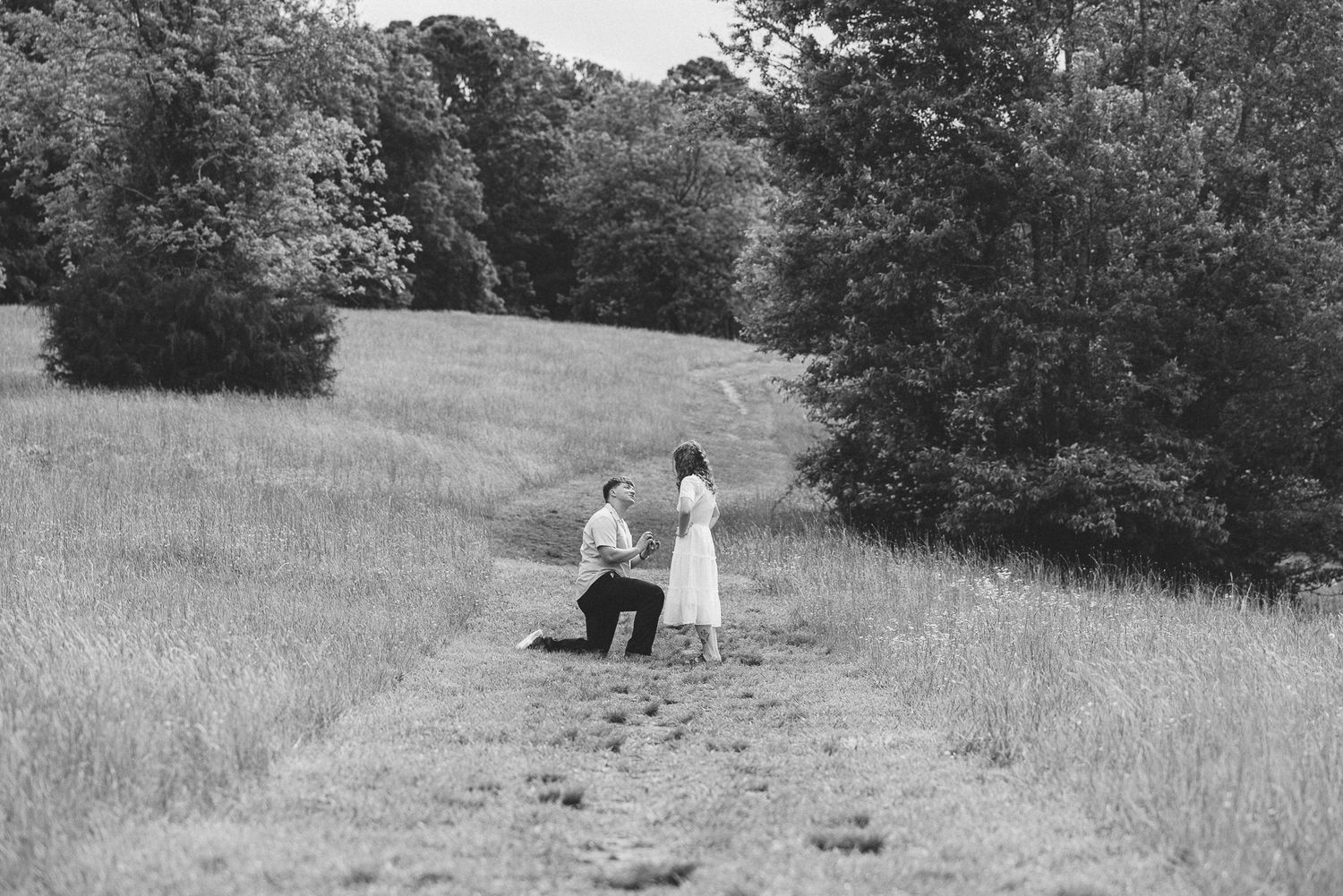 A black and white photograph of a couple in a peaceful meadow setting. Twickenham House Wedding Photographer