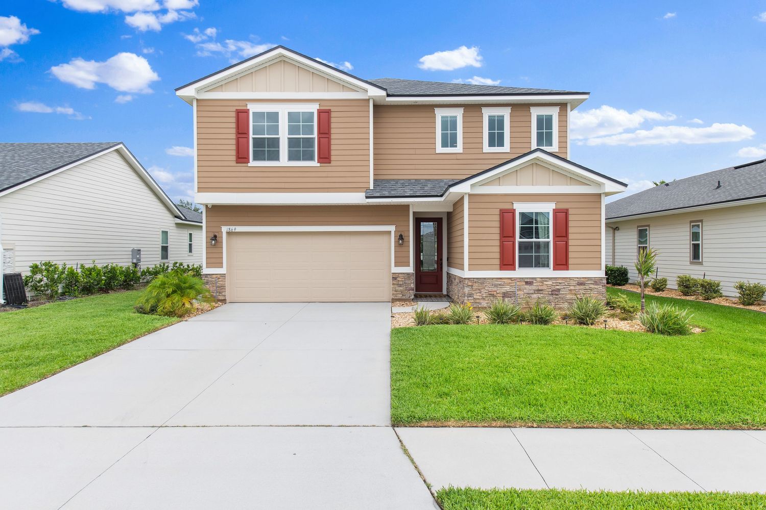 Two-story beige suburban home with attached garage and manicured lawn in Middleburg, Florida.
