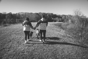 A black and white photo of a family walking down a path together while holding hands.