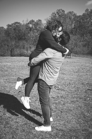 A joyful couple embraces in a spinning hug outdoors in black and white.