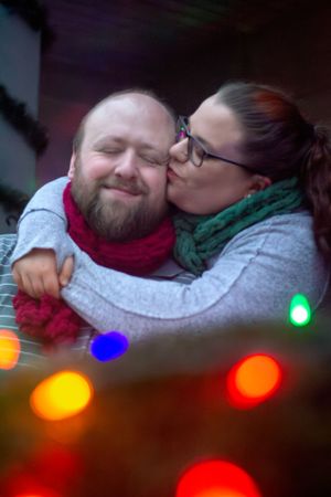 Cozy winter portrait with colorful holiday lights in the foreground.