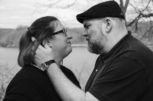 A tender black and white photo of a couple sharing an intimate moment outdoors.