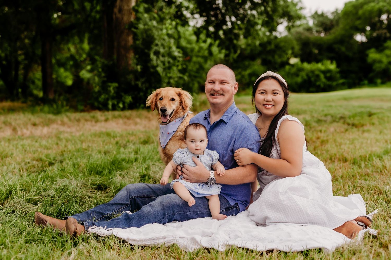 Family of four poses casually together among fall trees.