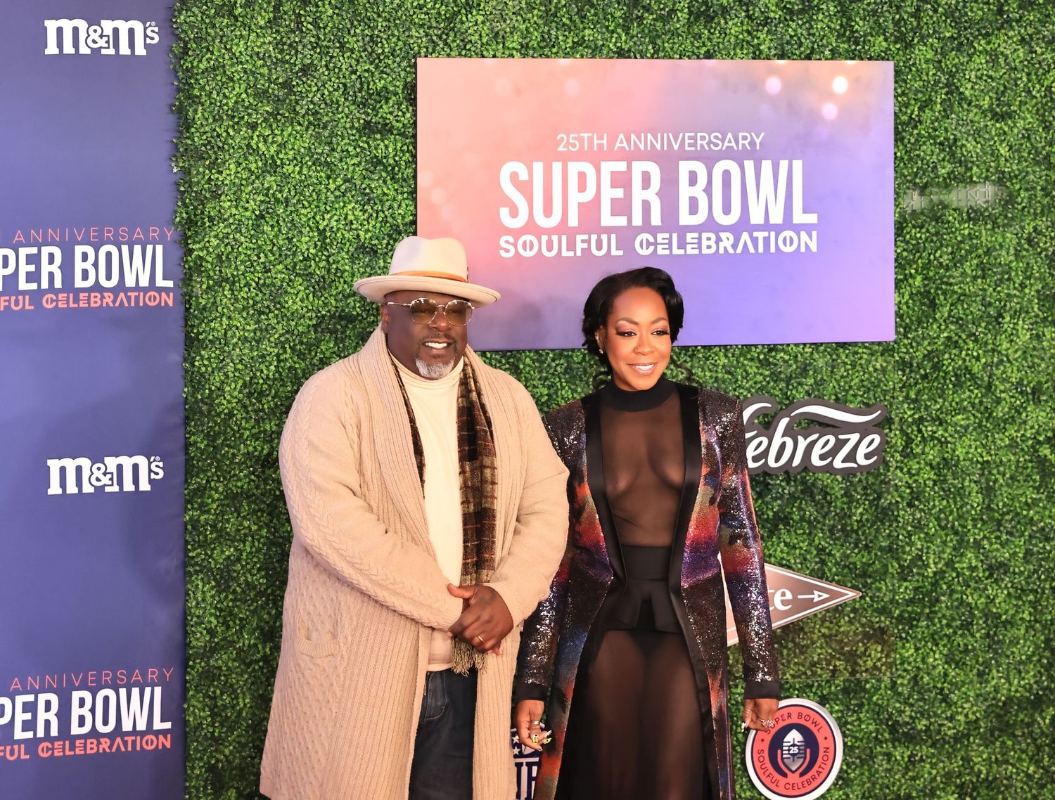 Two attendees pose at the 25th Anniversary Super Bowl Soulful Celebration event against a branded step-and-repeat backdrop.