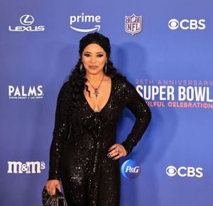 Guest in sparkling black gown strikes pose at Super Bowl celebration.
