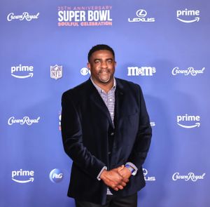 Guest in navy velvet jacket poses at Super Bowl celebration event.