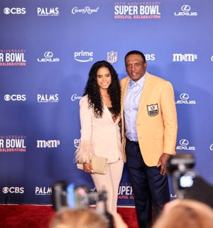 Couple poses at Super Bowl celebration with attendee wearing yellow blazer and formal attire.