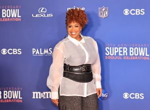 An attendee in sheer white top and belted waist poses at Super Bowl event.