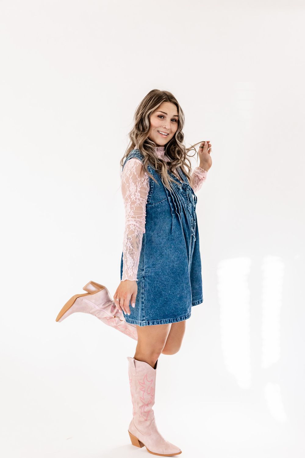 Wyoming Photographer
Fashion model in denim dress, pink lace sleeves and matching pink knee-high boots poses against white background.