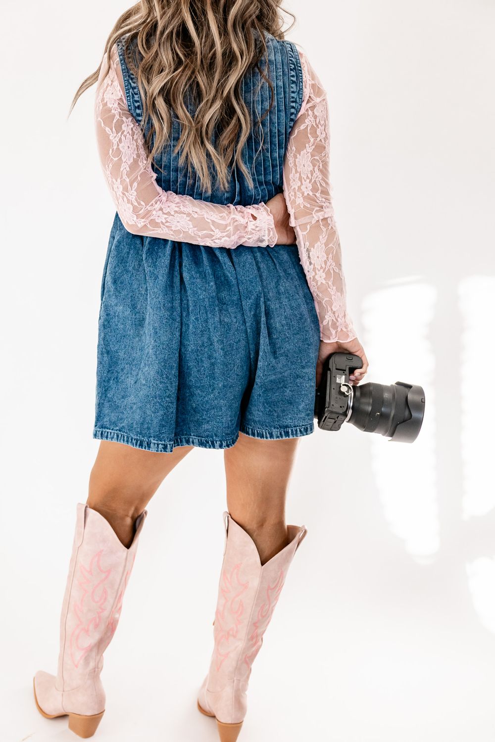 Wyoming Photographer
Back view of photographer in denim dress, pink lace top and pink cowboy boots holding professional camera.