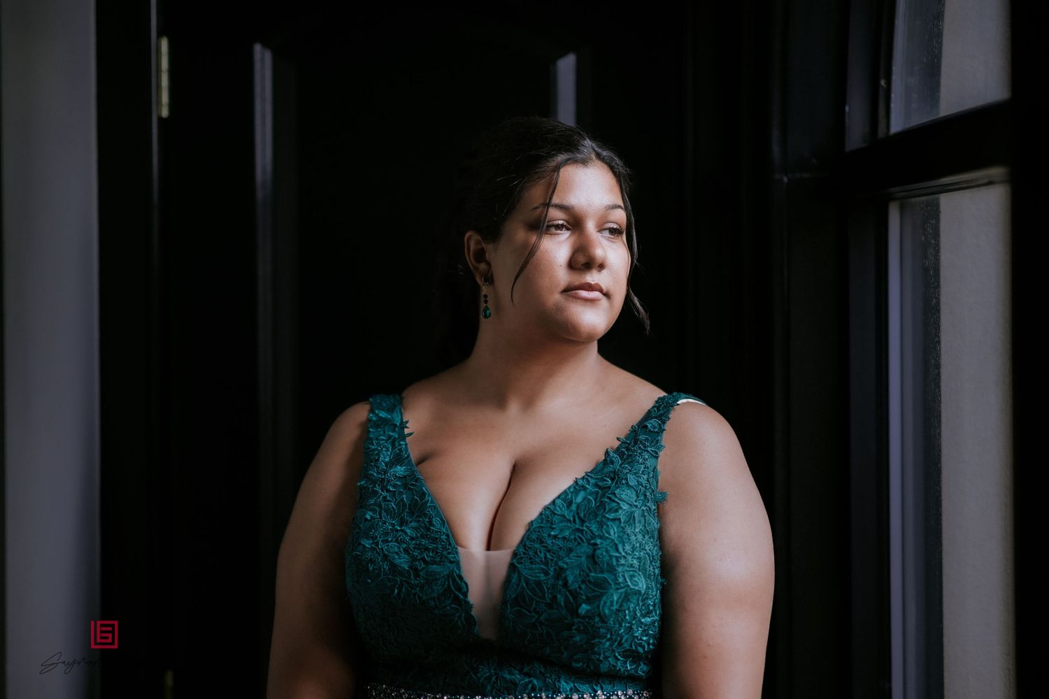 Dramatic window light portrait in emerald green formal dress.