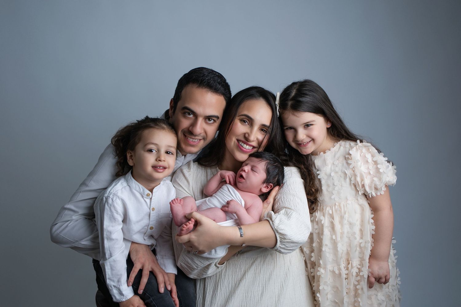 Posed studio portrait of parents with two siblings and newborn baby during family photography session