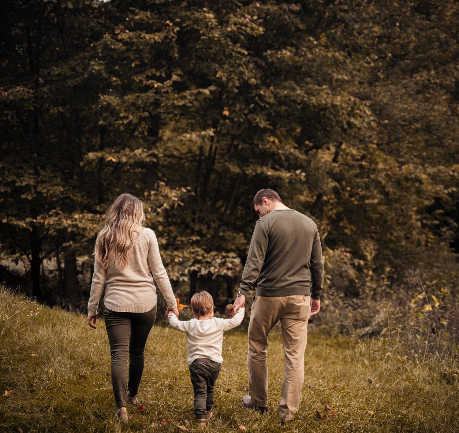 Family portrait on a wooden bridge with fall foliage in the background.