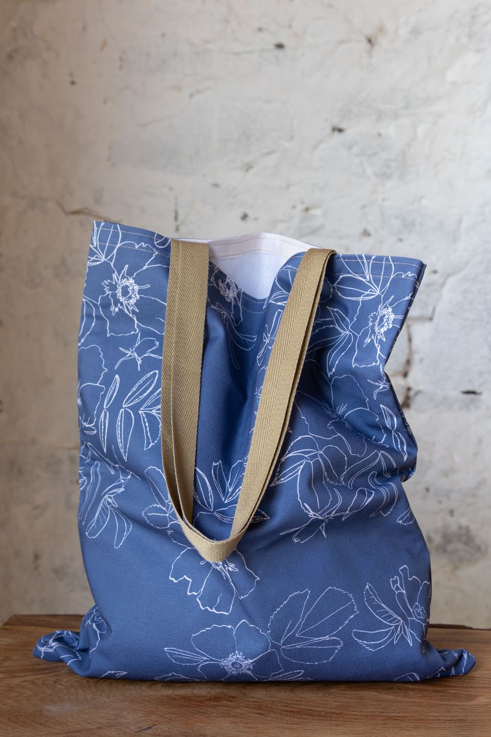 Blue tote bag with a white hand drawn flower botanical
