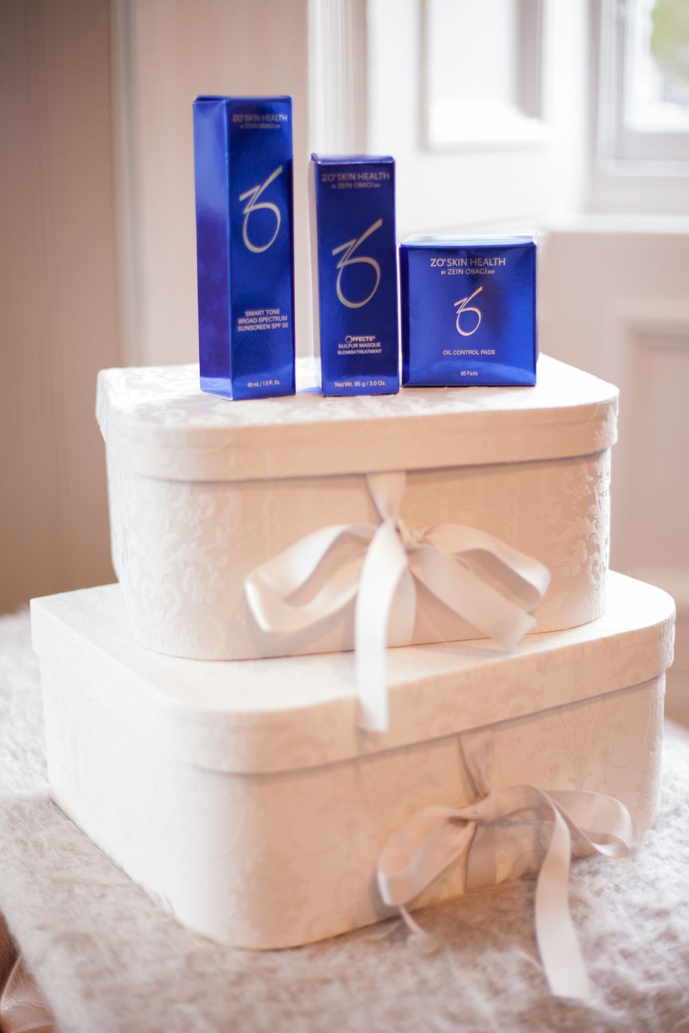 3 blue boxes of skin care products, sat on top of two white vanity style boxes.