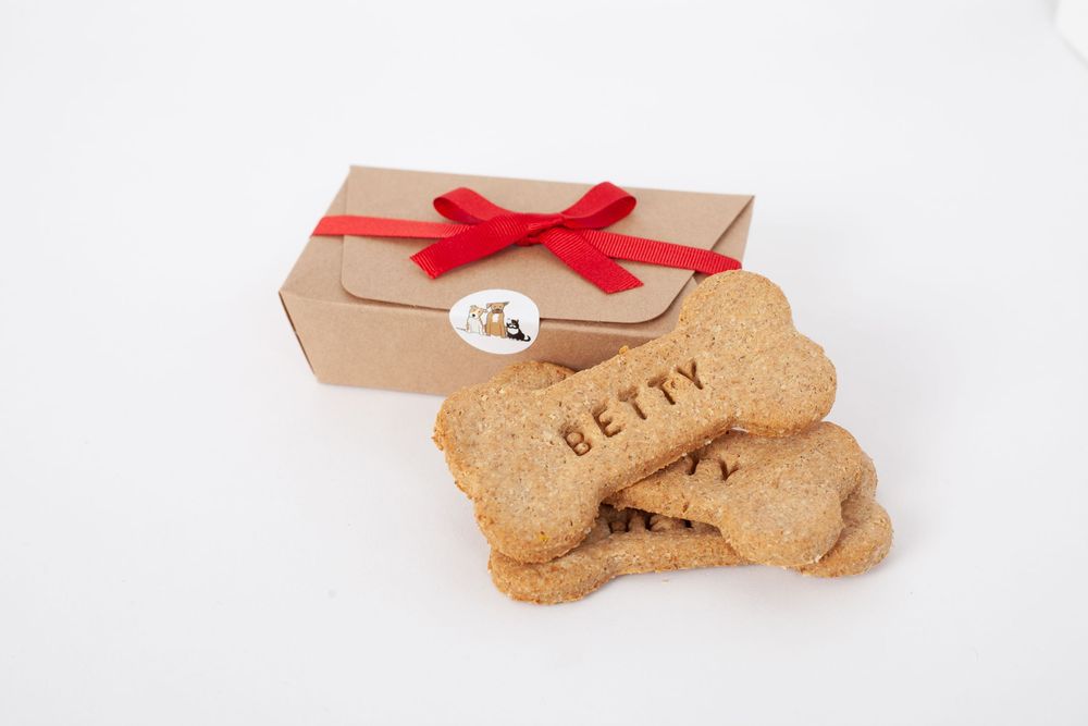 Box tied with a red ribbon and bone shaped biscuits sat in front, with Betty embossed into the biscuit centred on a white background.