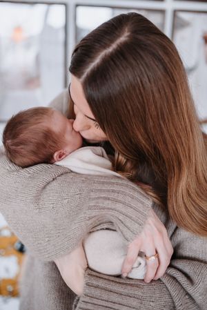 Two people embrace in a tender hug while wearing cozy beige sweaters in a bright interior setting.