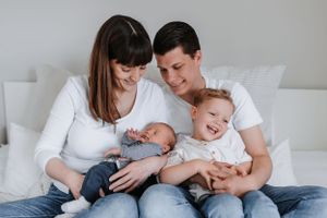 Young family shares intimate moment on white couch with their two children.