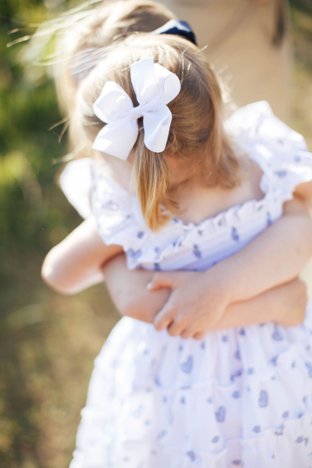 a girl carries her young sister. only the back of one girl's heads is visible