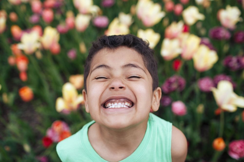 Everett family photographer: a close up of a young boy's smiling face with tulips in the background at the Skagit Valley Tulip Festival