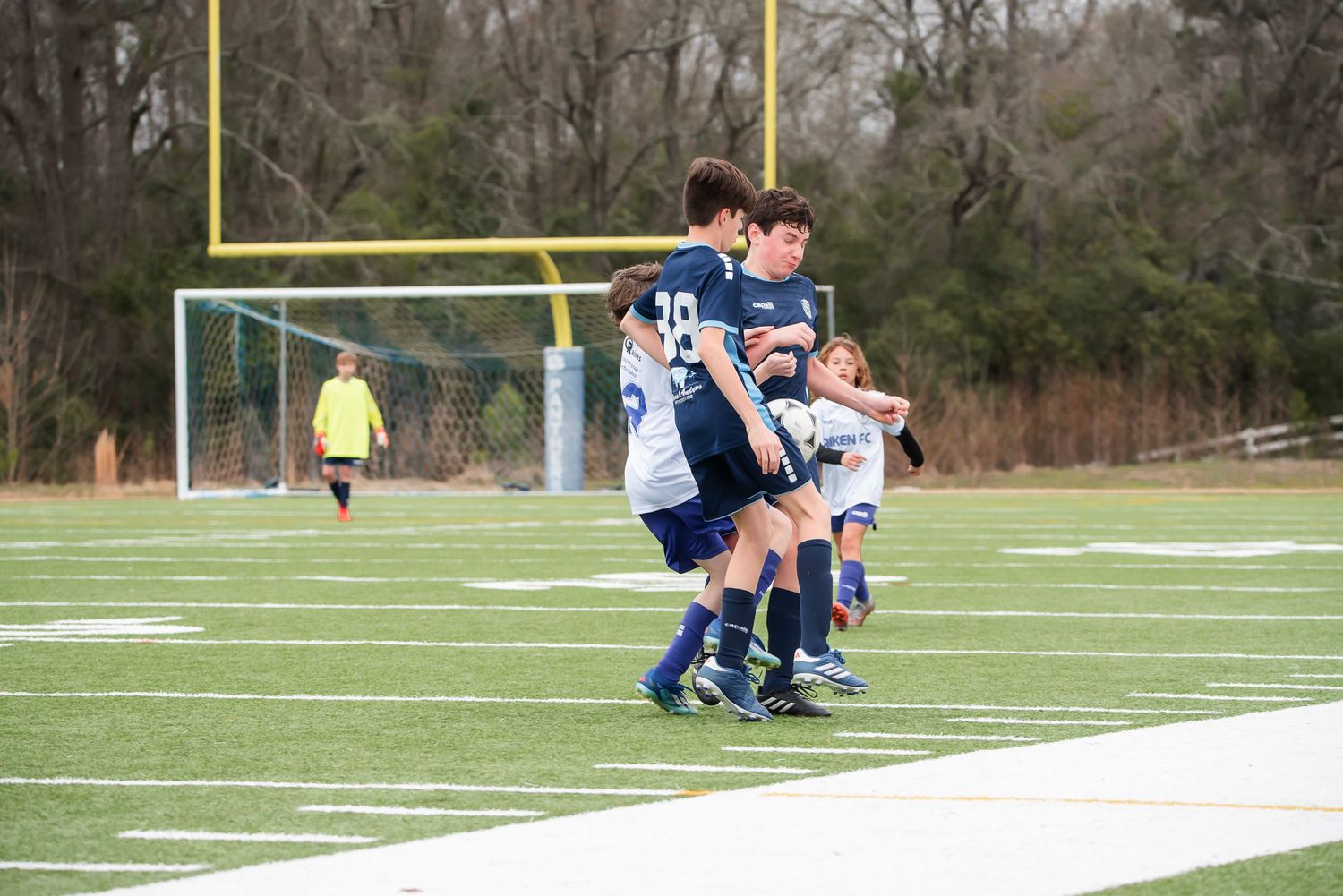 Soccer players leap for a ball during an intense match on a turf field.