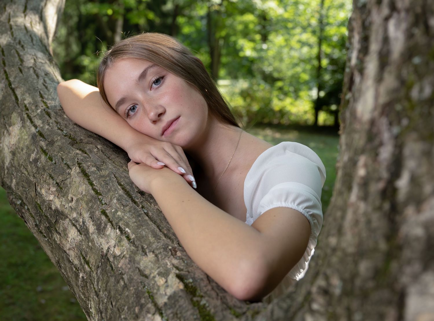 Artistic portrait of person resting against tree trunk in natural outdoor setting.