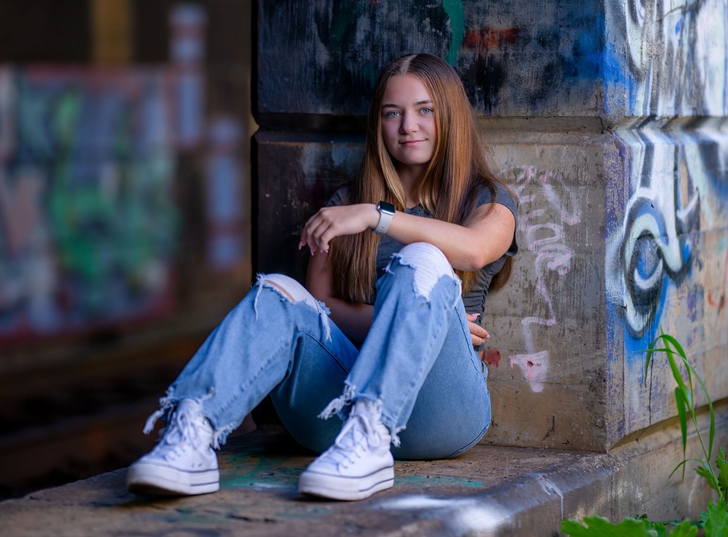 Casual portrait session with denim and white sneakers against urban backdrop.