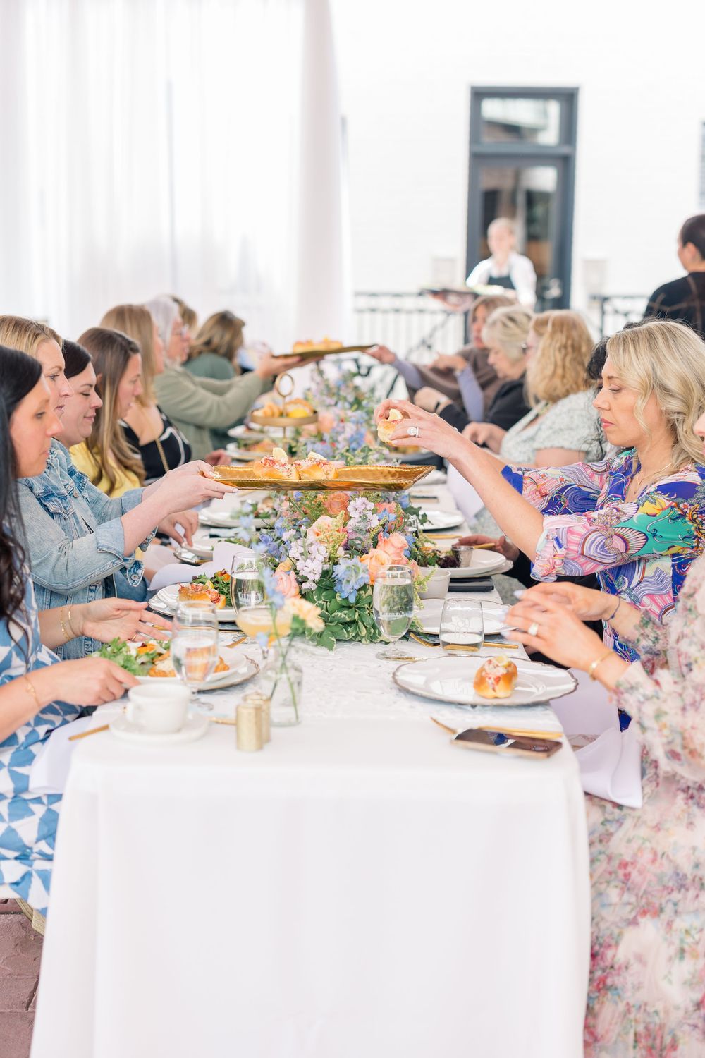 Guests seated at an elegant white-clothed dining table enjoying a catered meal at a formal event.