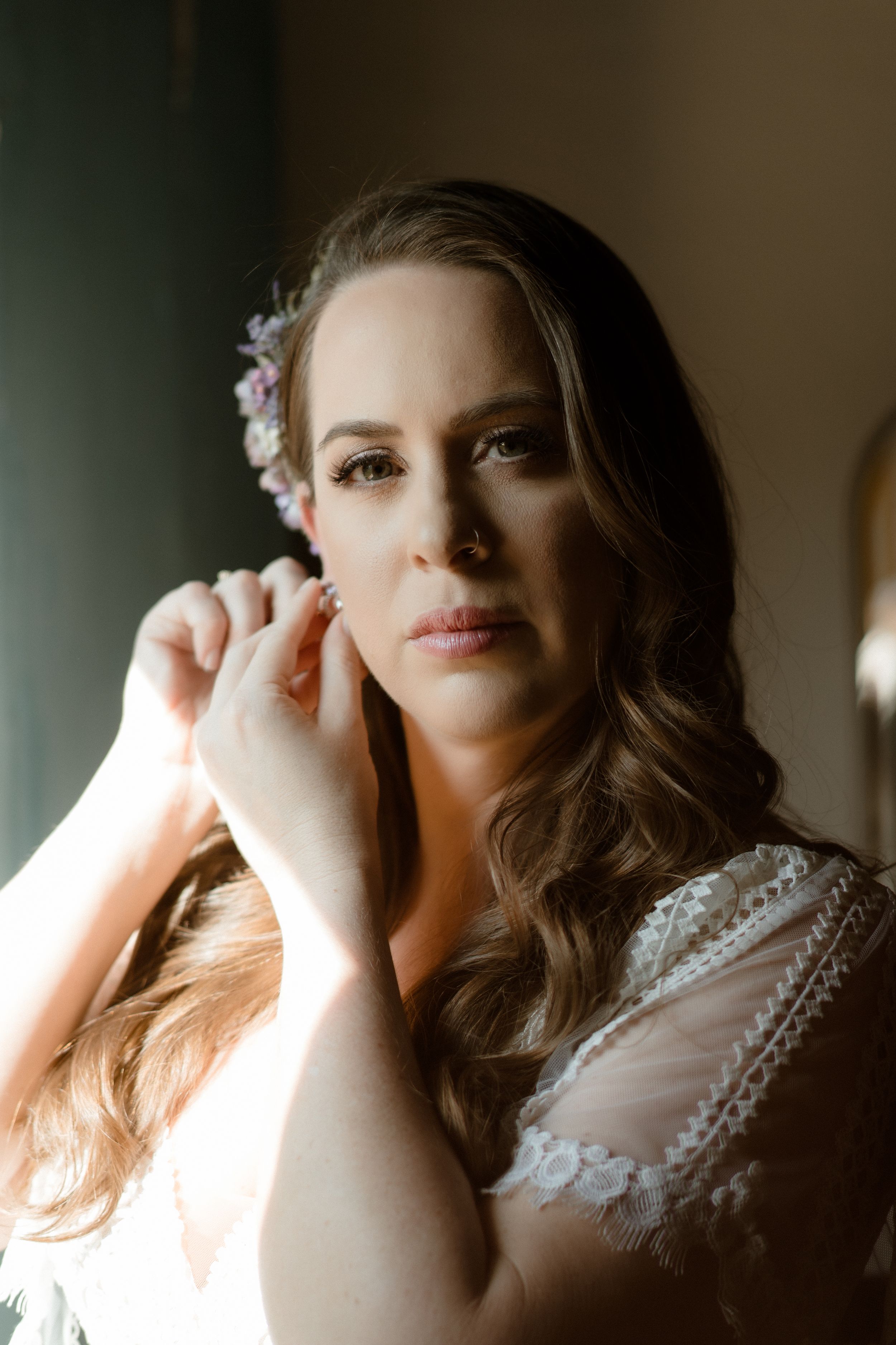 Wedding day preparation captured in moody natural lighting.