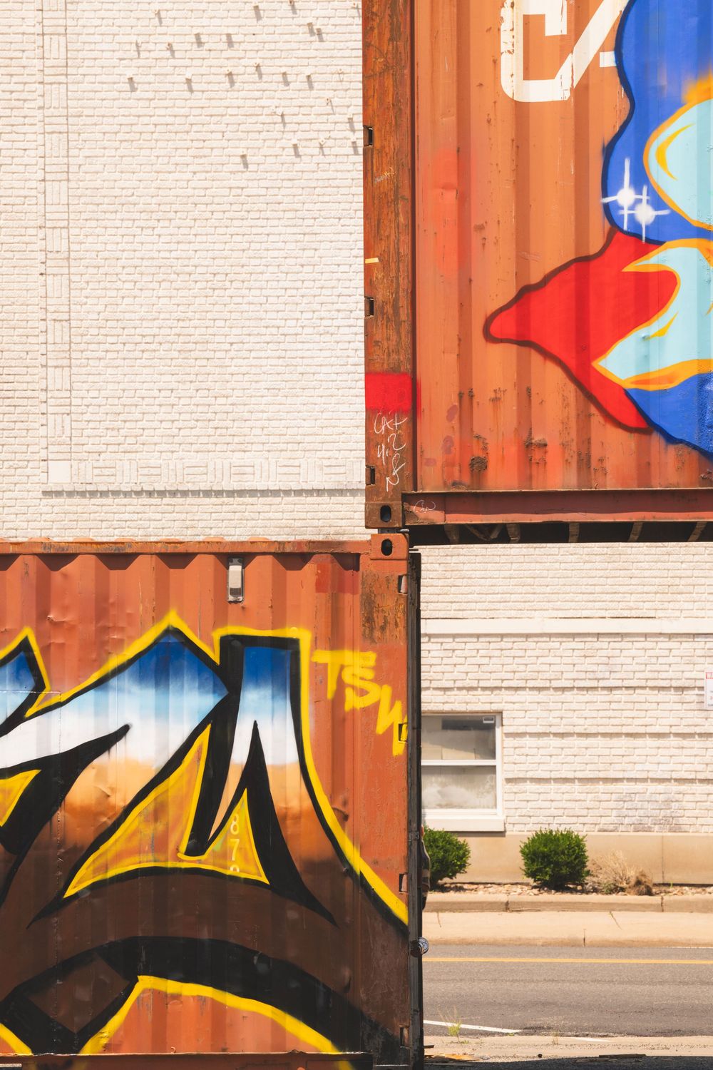 Urban wall featuring a mix of white brick and wooden panels with bold graffiti art in blue and red tones.