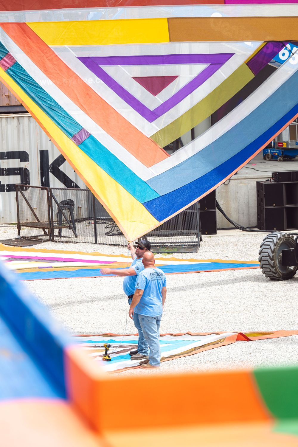 Colorful geometric mural being painted on a white wall with vibrant triangular patterns in orange, blue, and purple.