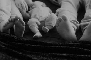 Black and white image of baby feet resting on textured fabric.