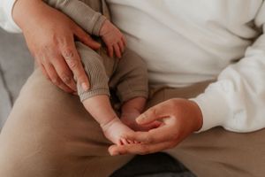 Gentle hands holding tiny baby feet in intimate moment.