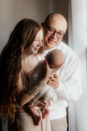 Family of three share an intimate moment together by a bright window.